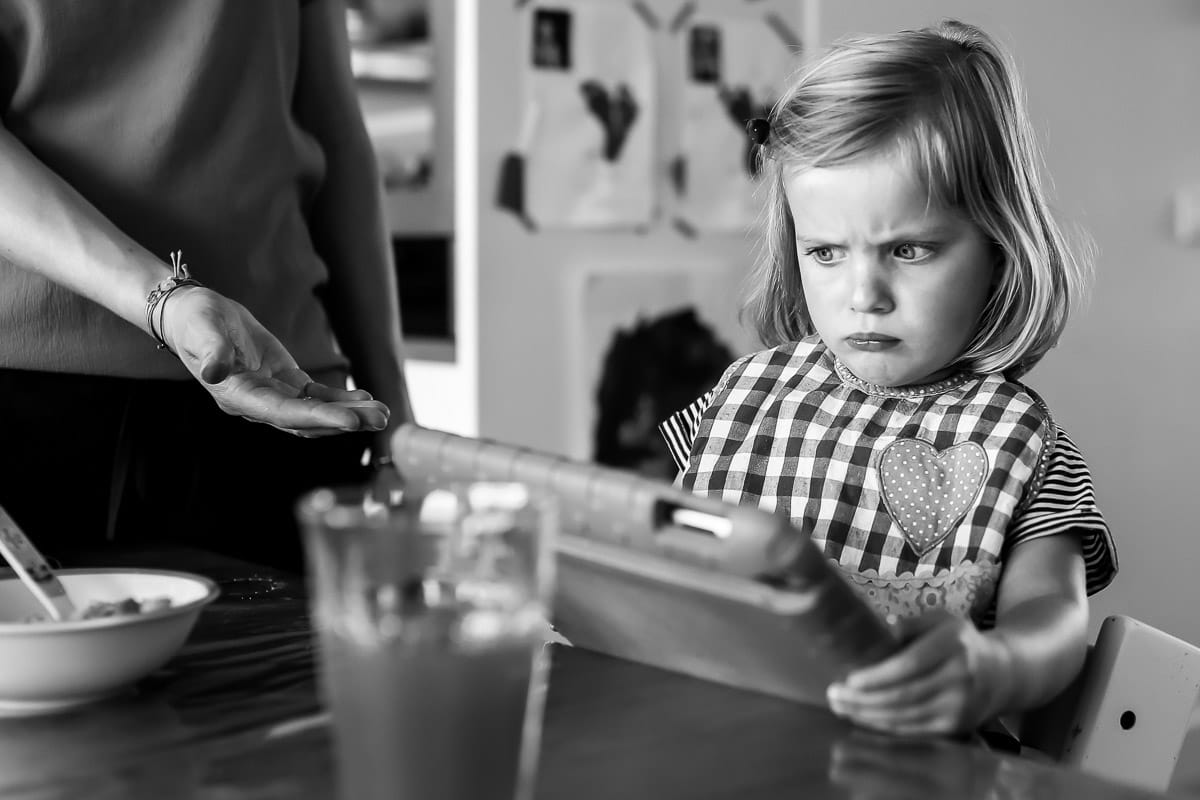 Fotograaf legt moment vast dat dochter boos is als ze haar tablet moet inleveren tijdens het eten